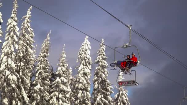 Ski lift bär skidåkare och snowboardåkare på berget. — Stockvideo