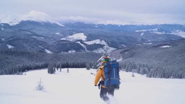 Un turista camina por la nieve en las montañas . — Vídeos de Stock