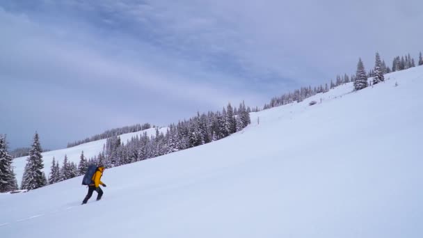 Tourist mit Rucksack erklimmt schneebedeckten Hang — Stockvideo