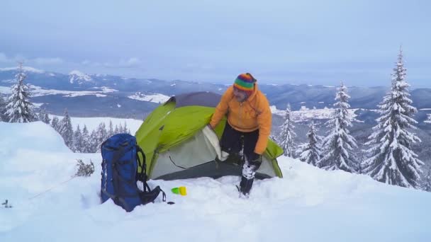 Un uomo con uno zaino viaggia tra le montagne invernali — Video Stock