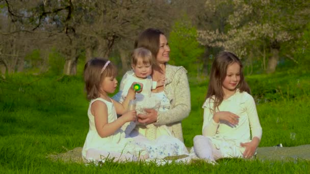 Мама с тремя дочерьми отдыхает в парке — стоковое видео