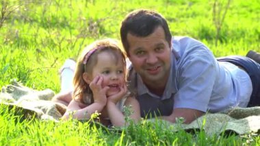 Mutlu baba ve kızı çimenlerin üzerinde dinleniyor.