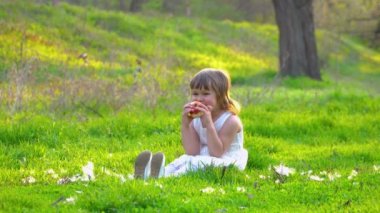 Çimenlerin üzerinde oturan ve elma yiyen kız