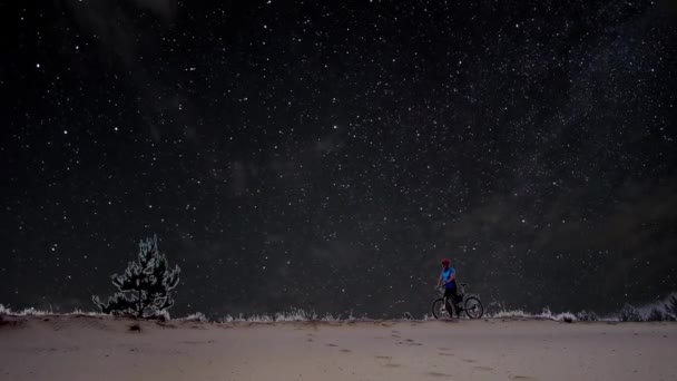 Man med en cykel på en bakgrund av stjärnhimmel — Stockvideo