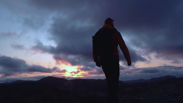 Silueta de un hombre de pie en la cima de la montaña — Vídeos de Stock