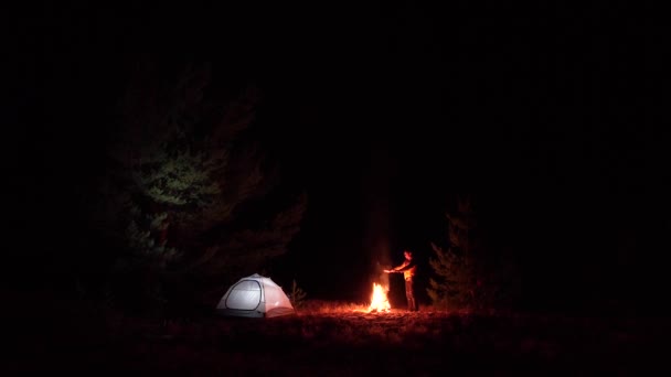 Un hombre cerca de un incendio por la noche — Vídeos de Stock