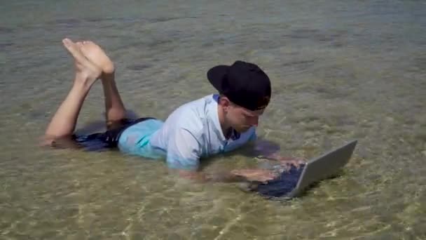 Een man werkt op vakantie. De man in de zee met een laptop. — Stockvideo