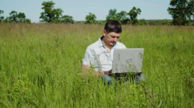 İşadamı Çimlerin Üzerinde Oturan Laptopun arkasında Çalışıyor