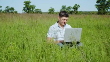 İşadamı Çimlerin Üzerinde Oturan Laptopun arkasında Çalışıyor