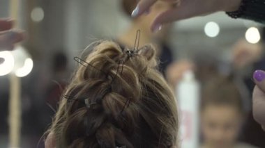 Kuaför bir kıza örgü örer.