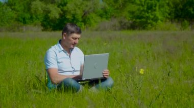 İşadamı Çimlerin Üzerinde Oturan Laptopun arkasında Çalışıyor