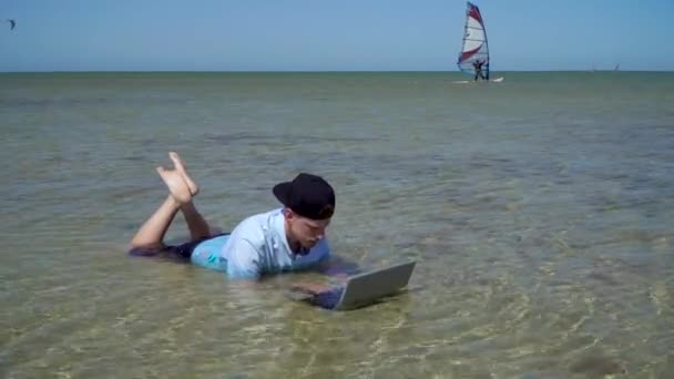 Een man werkt op vakantie. De man in de zee met een laptop. — Stockvideo