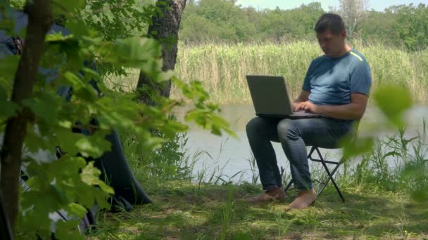 Empresário Trabalha atrás de um Laptopin perto da tenda na floresta — Vídeo de Stock