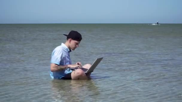 Een man werkt op vakantie. De man in de zee met een laptop. — Stockvideo