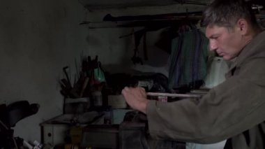 Bir adam eski bir atölyede çalışıyor.