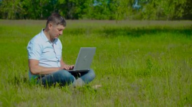 İşadamı Çimlerin Üzerinde Oturan Laptopun arkasında Çalışıyor