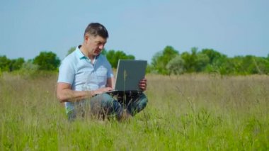 İşadamı Çimlerin Üzerinde Oturan Laptopun arkasında Çalışıyor