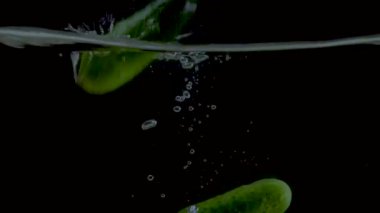 Salatalık yavaş çekim yakın çekim suya düşüyor.