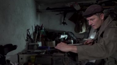 Bir adam eski bir atölyede çalışıyor.