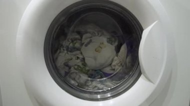Beyaz çamaşır makinesi kirli renkli giysileri yıkar.
