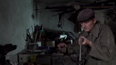 Bir adam eski bir atölyede çalışıyor.