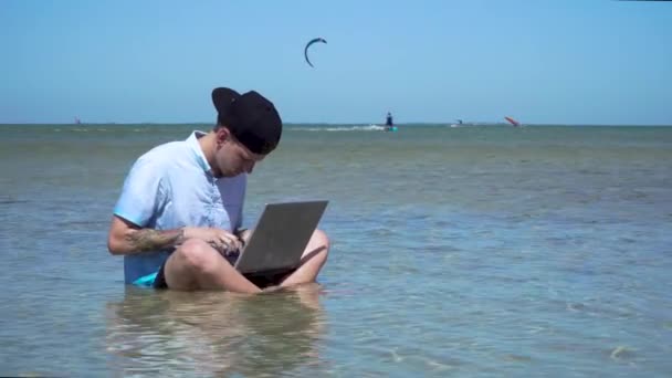 一个人在度假。那个在海里拿着手提电脑的家伙. — 图库视频影像