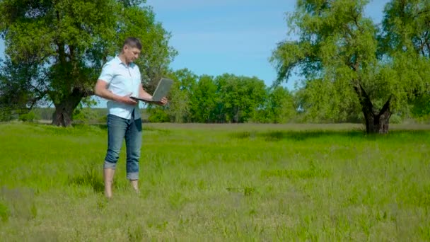 Zakenman werkt achter een laptop op het gazon — Stockvideo