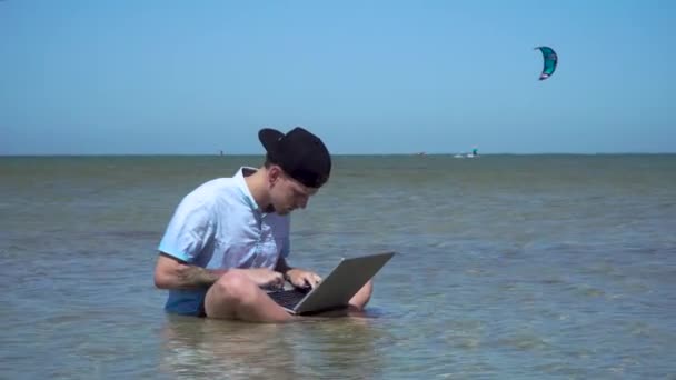 Een man werkt op vakantie. De man in de zee met een laptop. — Stockvideo