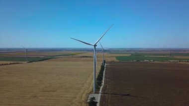 Rüzgarın gücüyle dönen yel değirmenlerinin havadan görünüşü ve yenilenebilir enerji üretimi. 4K