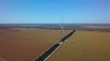 Rüzgarın gücüyle dönen yel değirmenlerinin havadan görünüşü ve yenilenebilir enerji üretimi. 4K