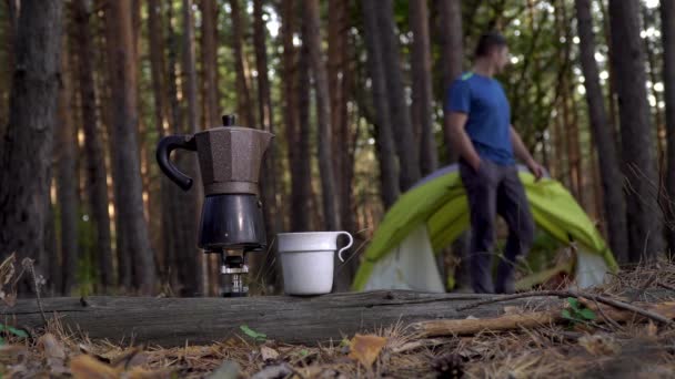 Ароматический кофе готовится в гейзере кофеварка и человек около палатки в лесу. — стоковое видео