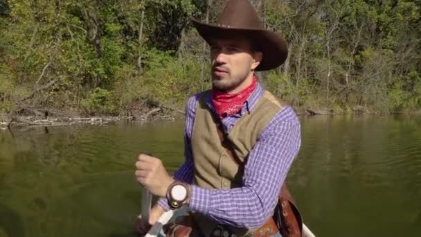 Cowboy em uma canoa flutua no rio — Vídeo de Stock