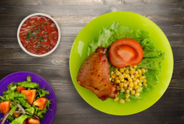 salata, Mısır ve domates bir tabakta tavuk kanadı. rustik bir arka plan üzerine Sebzeli tavuk kanadı