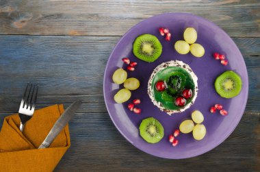 tatlı kek ve meyve (üzüm, kivi, nar) ahşap arka plan üzerinde. tatlı bir plaka Üstten Görünüm