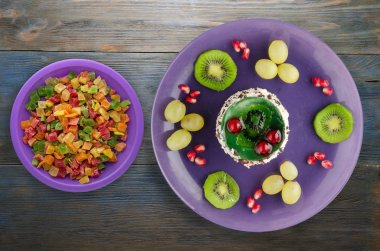 tatlı kek ve meyve (üzüm, kivi, nar) ahşap arka plan üzerinde. tatlı bir plaka Üstten Görünüm