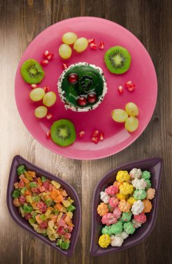 tatlı kek ve meyve (üzüm, kivi, nar) ahşap arka plan üzerinde. tatlı bir plaka Üstten Görünüm