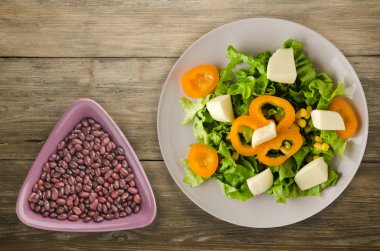  salata, peynir, salata, Mısır, biber ahşap arka plan üzerinde. Vejetaryen salata bir plaka üzerinde. Vejetaryen salata Üstten Görünüm