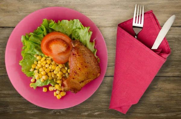 chicken wing with salad, corn and tomato on a plate. chicken wing with vegetables on a rustic background