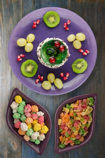 tatlı kek ve meyve (üzüm, kivi, nar) ahşap arka plan üzerinde. tatlı bir plaka Üstten Görünüm