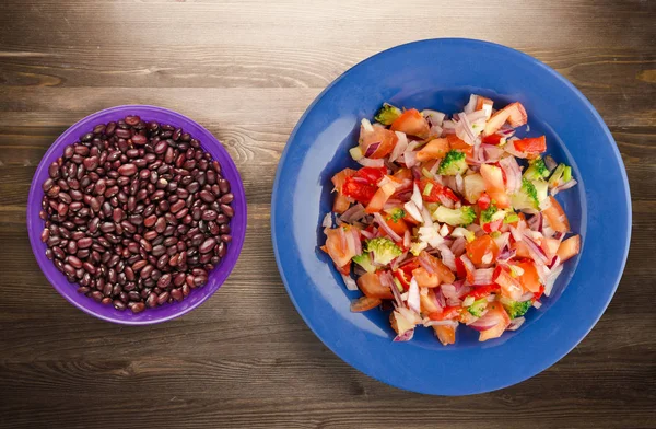 vegan gıda. salata bir tabakta sebze (biber, domates, soğan, brokoli) üzerinden. vegan salata ahşap arka plan üzerinde