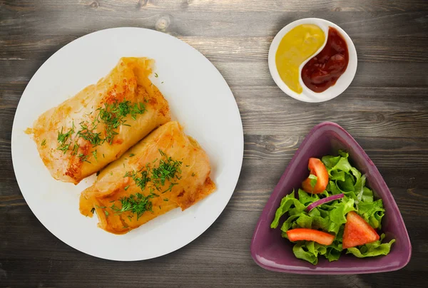 lahana bir tabak içinde alır. lahana bir ahşap arka plan üzerinde rulo. et lahana Üstten Görünüm.