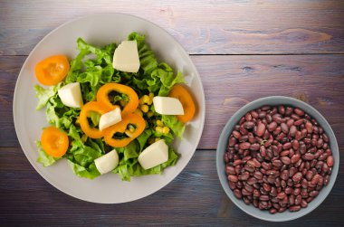  salata, peynir, salata, Mısır, biber ahşap arka plan üzerinde. Vejetaryen salata bir plaka üzerinde. Vejetaryen salata Üstten Görünüm