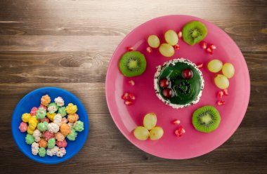 tatlı kek ve meyve (üzüm, kivi, nar) ahşap arka plan üzerinde. tatlı bir plaka Üstten Görünüm