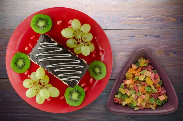 tatlı kek ve meyve (üzüm, kivi, nar) ahşap arka plan üzerinde. tatlı bir plaka Üstten Görünüm