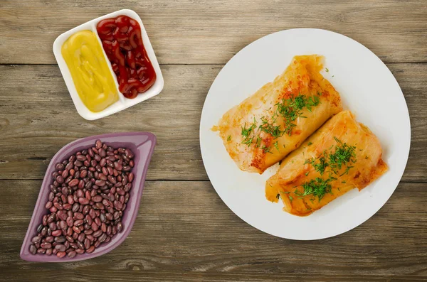 lahana bir tabak içinde alır. lahana bir ahşap arka plan üzerinde rulo. et lahana Üstten Görünüm.