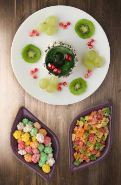 tatlı kek ve meyve (üzüm, kivi, nar) ahşap arka plan üzerinde. tatlı bir plaka Üstten Görünüm