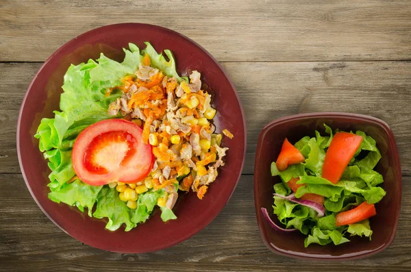 salad with chicken stomachs with carrots and corn and salad on a plate. chicken salad with vegetables on a wooden background