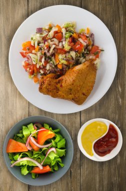 ahşap arka plan üzerinde sebze salatası ile tavuk kanadı. tavuk kanadı bir tabakta sebze ile.