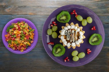 tatlı kek ve meyve (üzüm, kivi, nar) ahşap arka plan üzerinde. tatlı bir plaka Üstten Görünüm