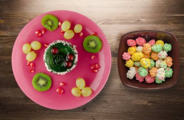 tatlı kek ve meyve (üzüm, kivi, nar) ahşap arka plan üzerinde. tatlı bir plaka Üstten Görünüm